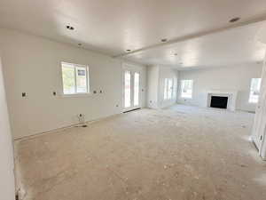 Unfurnished living room featuring a fireplace, a textured ceiling, and healthy amount of natural light