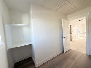Unfurnished bedroom featuring dark wood-style flooring and attic access