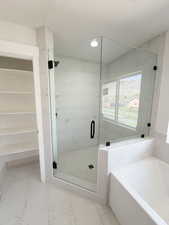 Bathroom featuring a garden tub, a shower stall, light marble finish floors, and recessed lighting