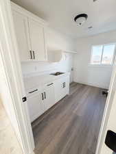Laundry area with dark wood finished floors and cabinet space