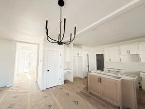 Kitchen featuring a kitchen island, white cabinetry, a chandelier, and hanging light fixtures