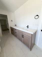 Bathroom with double vanity and light marble finish floors