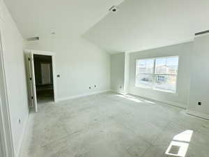 Unfurnished room with concrete flooring and vaulted ceiling