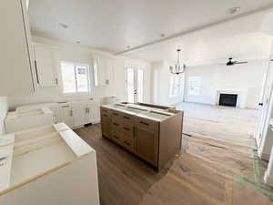 Kitchen with white cabinets, a fireplace, a center island, and a chandelier