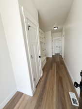 Hallway featuring wood-finish flooring, white built-in cabinetry with paneled doors, and a flush-mount ceiling light