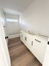 Full bathroom with double vanity, dark wood finished floors, and bathing tub / shower combination