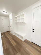 Entryway featuring a built-in bench with integrated shelving, overhead cubbies, and coat hooks