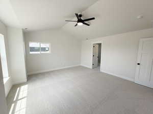 Spacious room featuring vaulted ceilings, a contemporary black ceiling fan, light gray carpeting, and multiple windows
