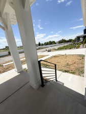 Front porch featuring white columns, a modern black metal handrail, and concrete steps