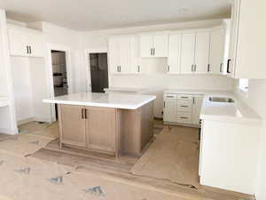 Dual tone kitchen with two tone cabinetry, a center island, wood finished floors, recessed lighting, and light stone counters