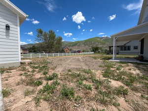 Expansive lot featuring mountain scenery and a white three-rail fence