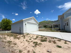 Detached single-car garage featuring light-toned horizontal siding, white trim, and a white panel garage door