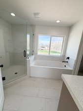 Full bath with a bath, a shower stall, vanity, light marble finish flooring, and recessed lighting