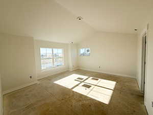 Spare room featuring baseboards and vaulted ceiling