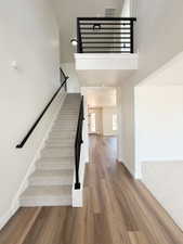 Two-story entry foyer featuring wood-finish flooring, a carpeted staircase with contemporary black metal railings, and a second-story landing with matching railings