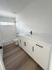 Bathroom featuring vanity, dark wood finished floors, and  shower combination
