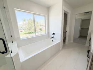 Soaking tub with black matte fixtures, set against a large window