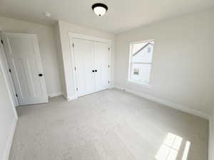 Neutral tone carpeting complemented by white walls, a white trim package, and a flush mount ceiling light fixture