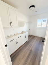 Washroom featuring dark wood finished floors, washer hookup, and cabinet space