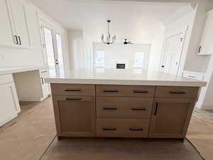 Dual tone kitchen with two tone cabinetry, a kitchen island, a fireplace, hanging lights, and open floor plan