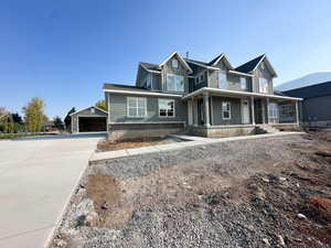 View of front facade with an outbuilding, covered porch, a detached garage, and board and batten siding
