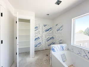 Bathroom with a bath and unfinished concrete flooring