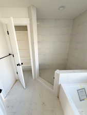 Bathroom featuring light marble finish floors, a garden tub, and a walk in shower