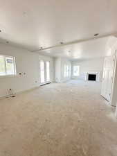Unfurnished living room with a fireplace, a textured ceiling, and french doors