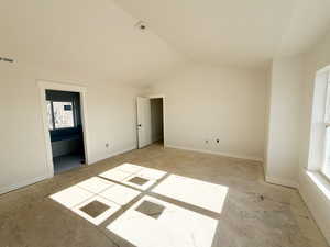 Unfurnished bedroom with lofted ceiling and ensuite bathroom