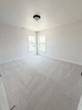 Spacious room with light-toned patterned carpeting and a neutral wall palette