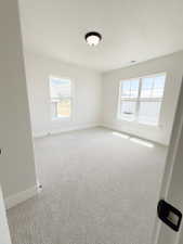 Spacious room featuring light-toned patterned carpeting and white walls