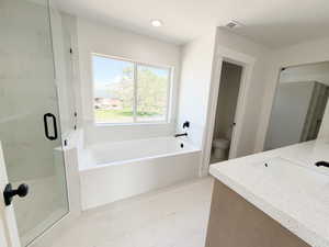 Soaking tub with black fixtures, framed window, and tiled surround