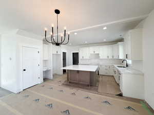 Kitchen with a chandelier, light stone countertops, a center island, dual tone cabinetry, and a breakfast bar area