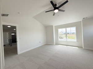 Spacious room with light-toned patterned carpet, a vaulted ceiling, and a contemporary ceiling fan