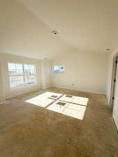 Spare room featuring vaulted ceiling and baseboards
