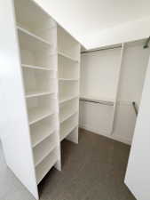 Custom closet system featuring white shelving units, multiple hanging rods, and textured carpeting