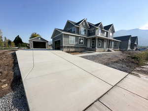 View of front of home with an outdoor structure, a garage, a porch, a mountain view, and concrete driveway