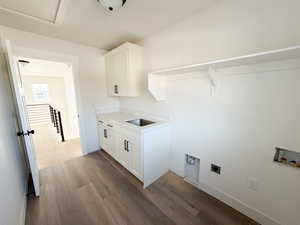 Laundry room with dark wood-style flooring, cabinet space, hookup for an electric dryer, and washer hookup