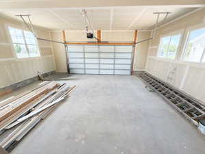 Spacious garage featuring a concrete floor, two windows, and an overhead garage door with opener