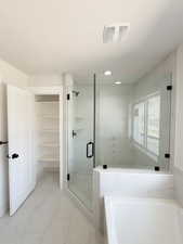Bathroom featuring a marble finish shower, light marble finish floors, a garden tub, and a textured ceiling