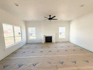 Unfurnished living room with a fireplace, healthy amount of natural light, and ceiling fan