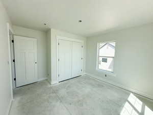 Unfurnished bedroom with concrete flooring and a closet