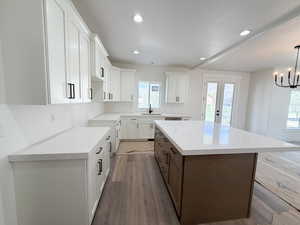 Dual tone kitchen with dual tone cabinetry, a kitchen island, dark wood-type flooring, french doors, and light stone counters