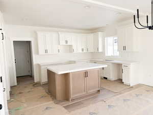 Kitchen with a center island, dual tone cabinets, and decorative light fixtures