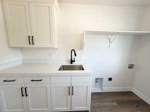Dedicated laundry area featuring white shaker-style cabinetry, a speckled countertop, and a stainless steel utility sink with a matte black faucet