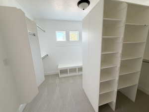 Custom walk-in closet featuring built-in shelving, hanging rods, and a storage bench