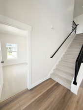 Staircase featuring black metal railings and light-toned carpeted treads
