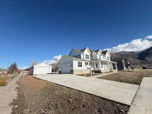 View of front facade featuring covered porch, stone siding, concrete driveway, and a mountain view