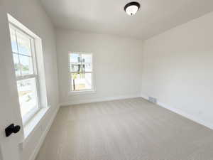 Bright interior space featuring light-toned walls, neutral patterned carpeting, and white baseboards