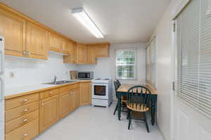 Kitchen featuring white electric stove, tasteful backsplash, light countertops, and stainless steel microwave